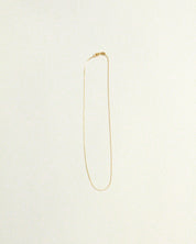 Gold necklace on a light beige background