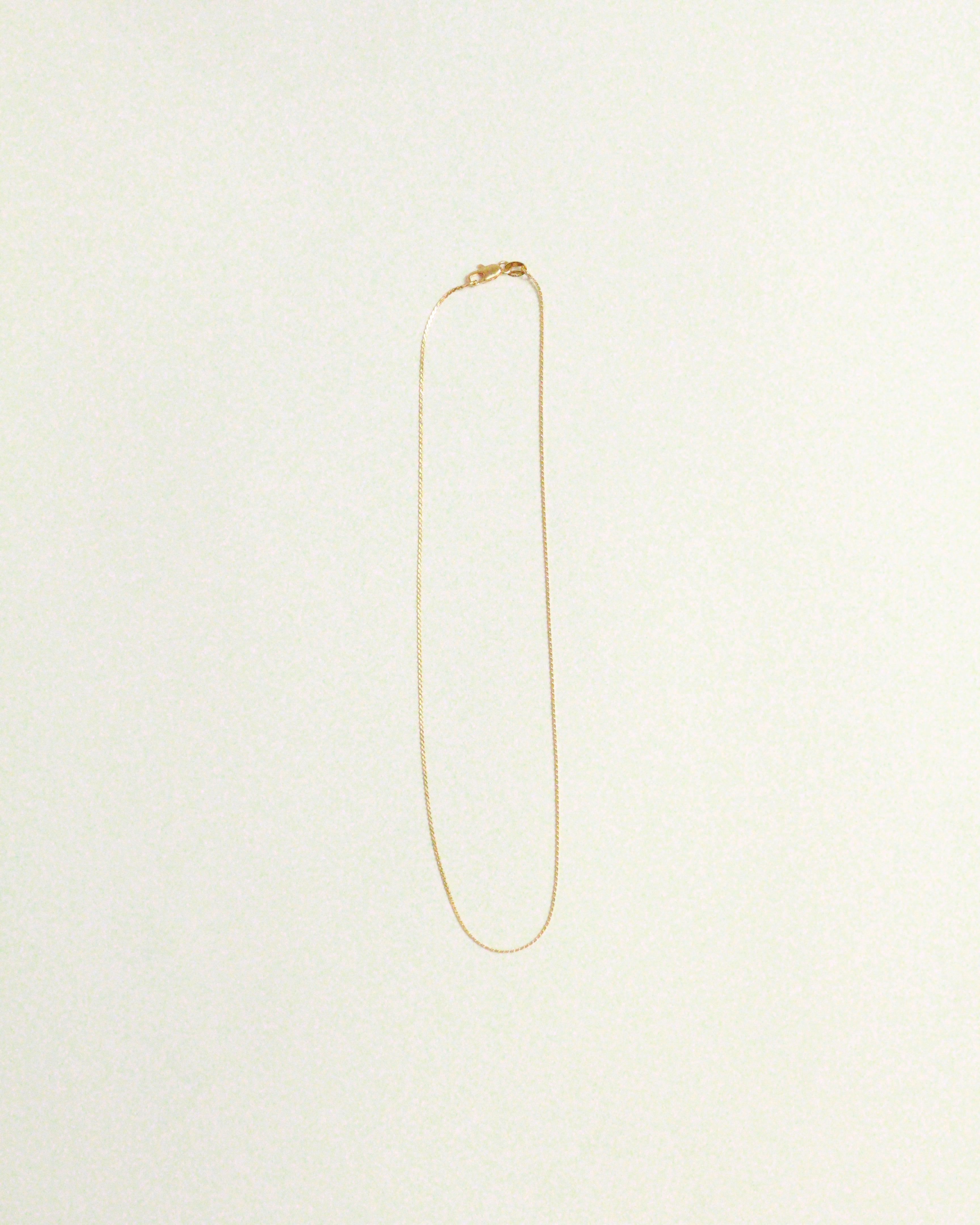 Gold necklace on a light beige background