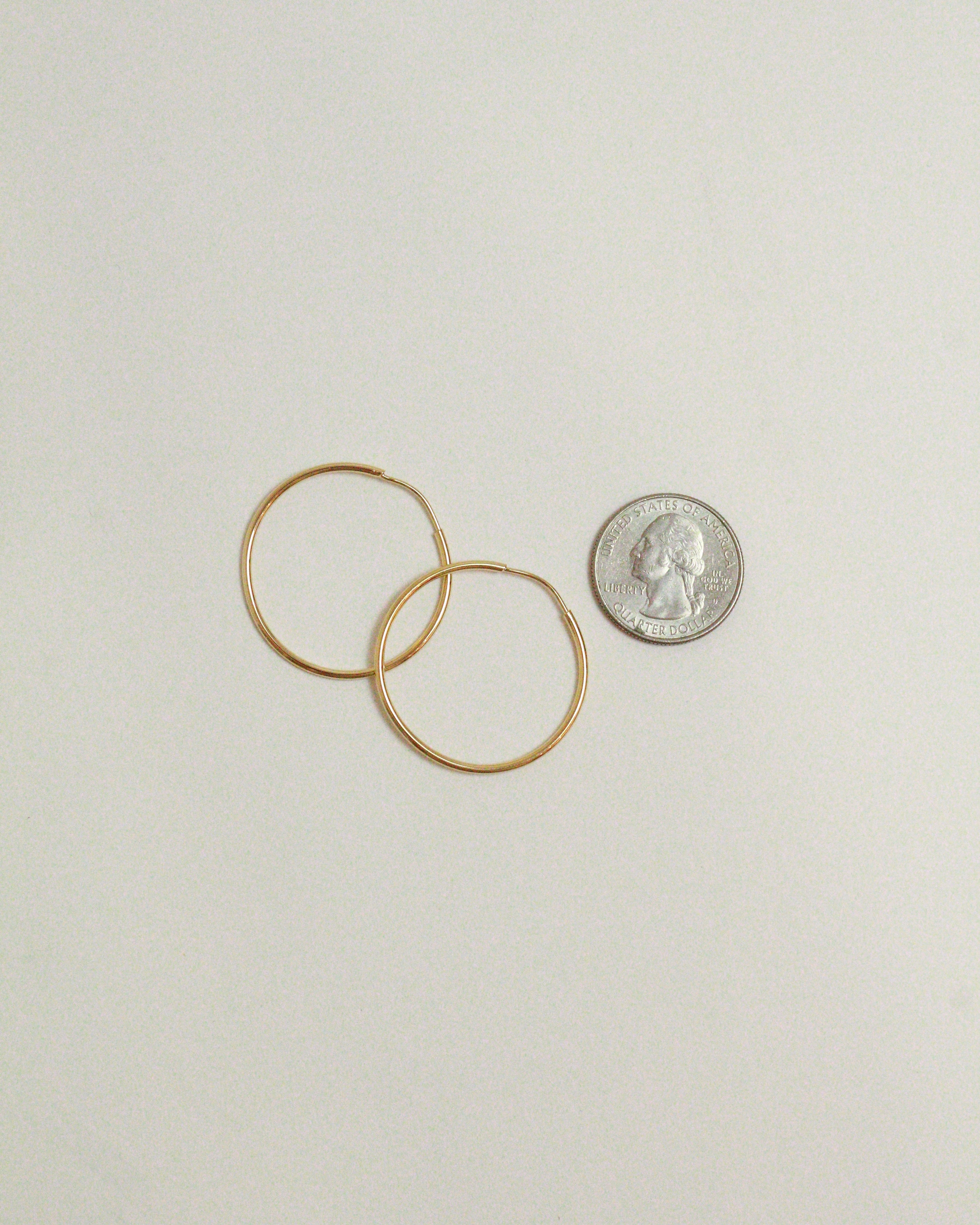 Two gold rings and a silver coin on a light gray background