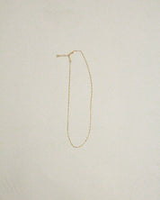 Gold necklace on a light beige background