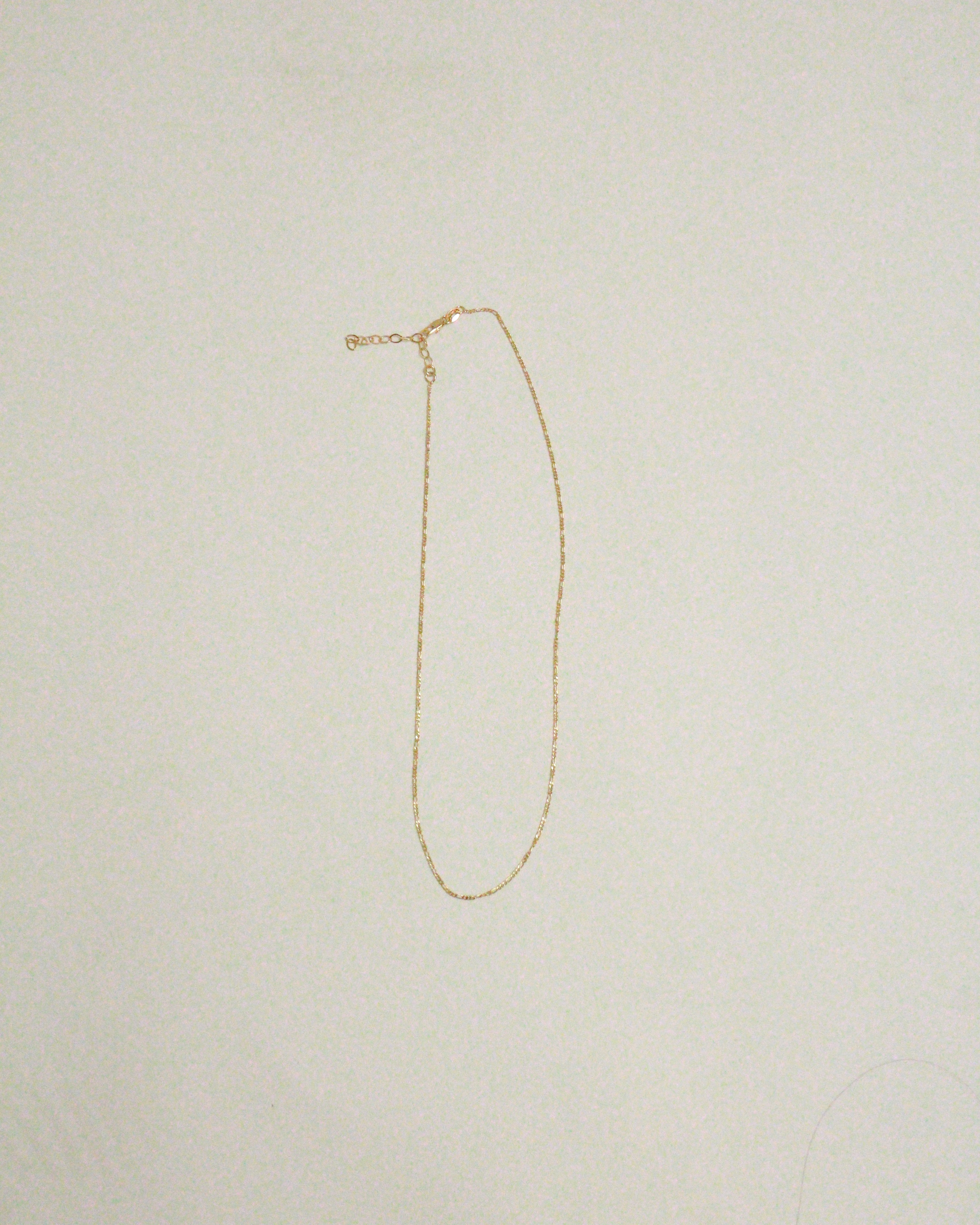 Gold necklace on a light beige background