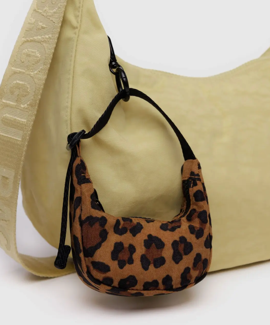 Leopard print bag charm attached to a beige bag on a white background