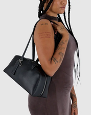 Person holding a black handbag against a plain background