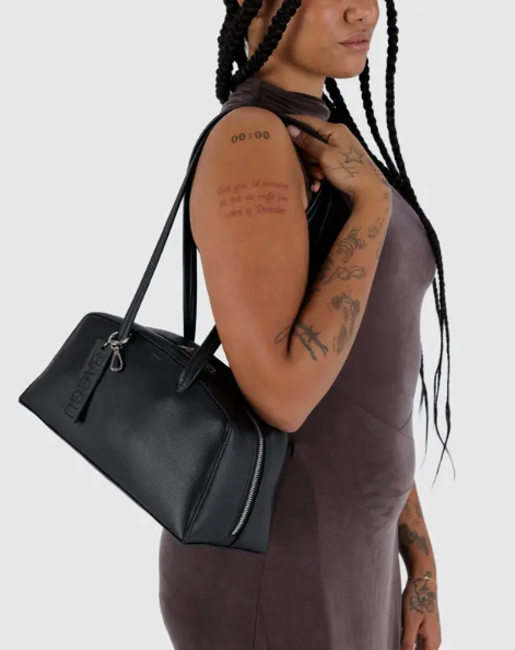 Person holding a black handbag against a plain background