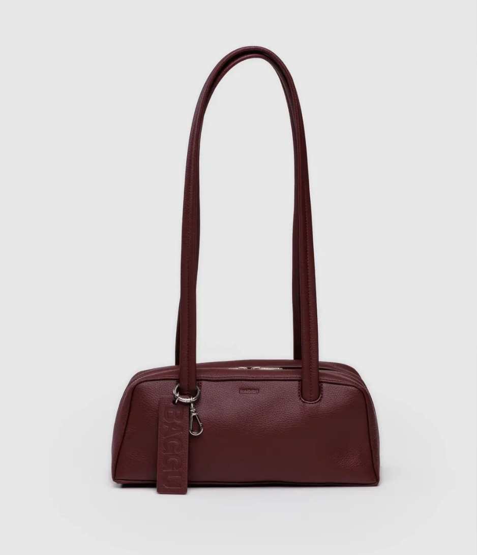 Burgundy handbag with a shoulder strap on a light gray background