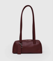 Burgundy handbag with a shoulder strap on a light gray background