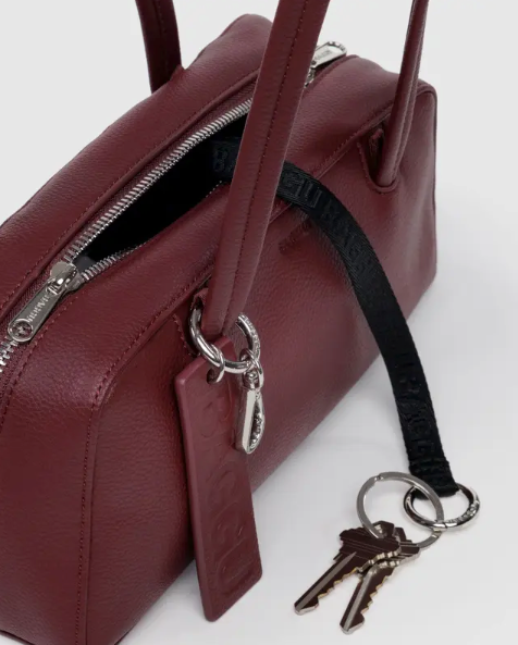 Maroon handbag with a keychain and keys on a white background