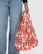 Person holding a red and white patterned bag with blue jeans on a white background