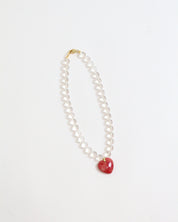 Necklace with a red puffy heart pendant and clear quartz beads on a white background