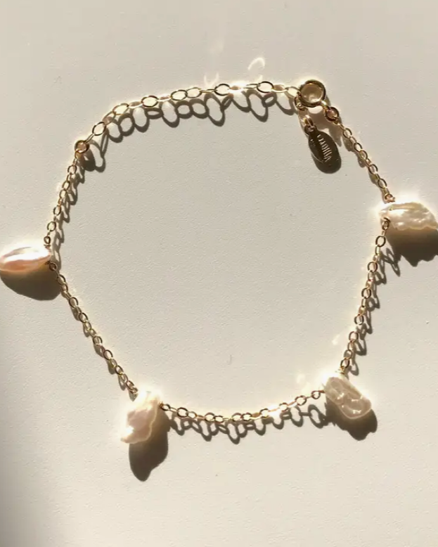 Bracelet with freshwater pearl charms on a light gray background