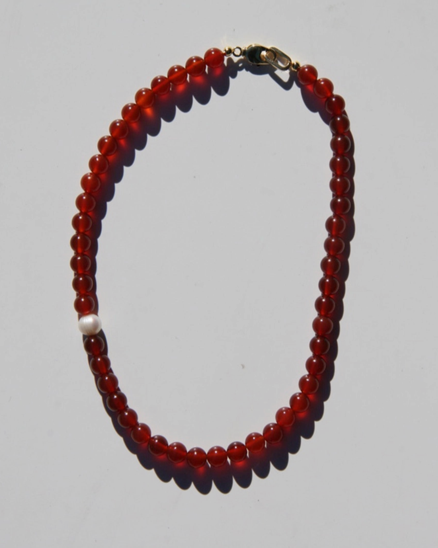 Beaded necklace with red beads on a gray background
