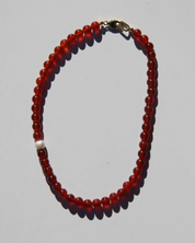 Beaded necklace with red beads on a gray background