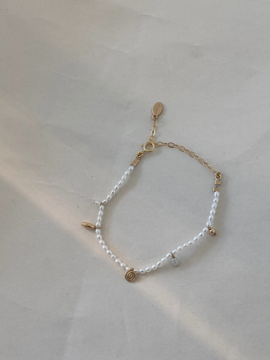 Bracelet with white beads and gold accents on a light gray background
