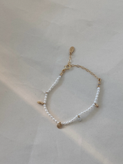 Bracelet with white beads and gold accents on a light gray background