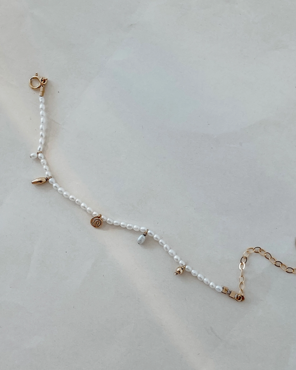 Pearl bracelet with gold accents on a light gray background