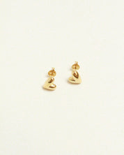 Gold heart-shaped earrings on a light beige background