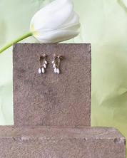 Marida Jewelry Pair of earrings on a stone block with a white tulip in the background
