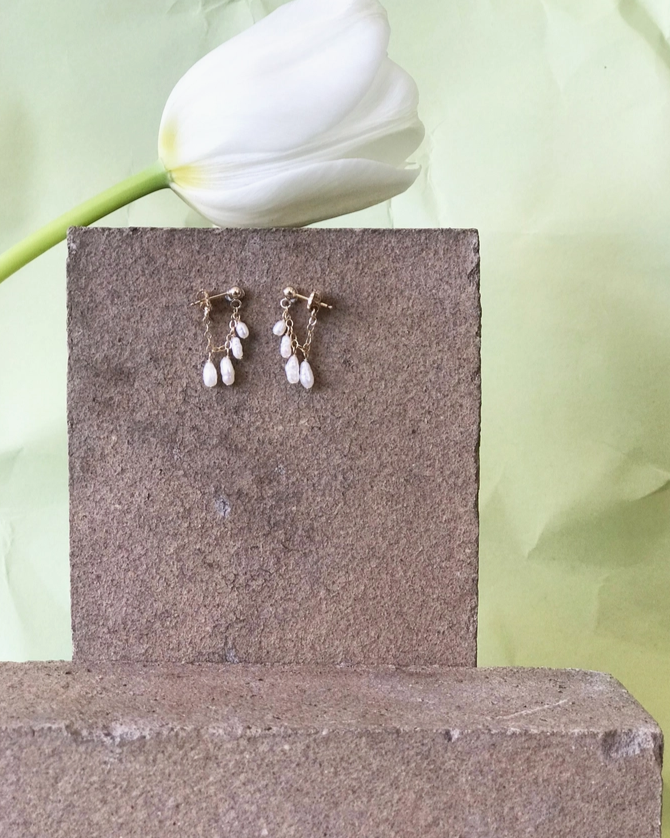Marida Jewelry Pair of earrings on a stone block with a white tulip in the background
