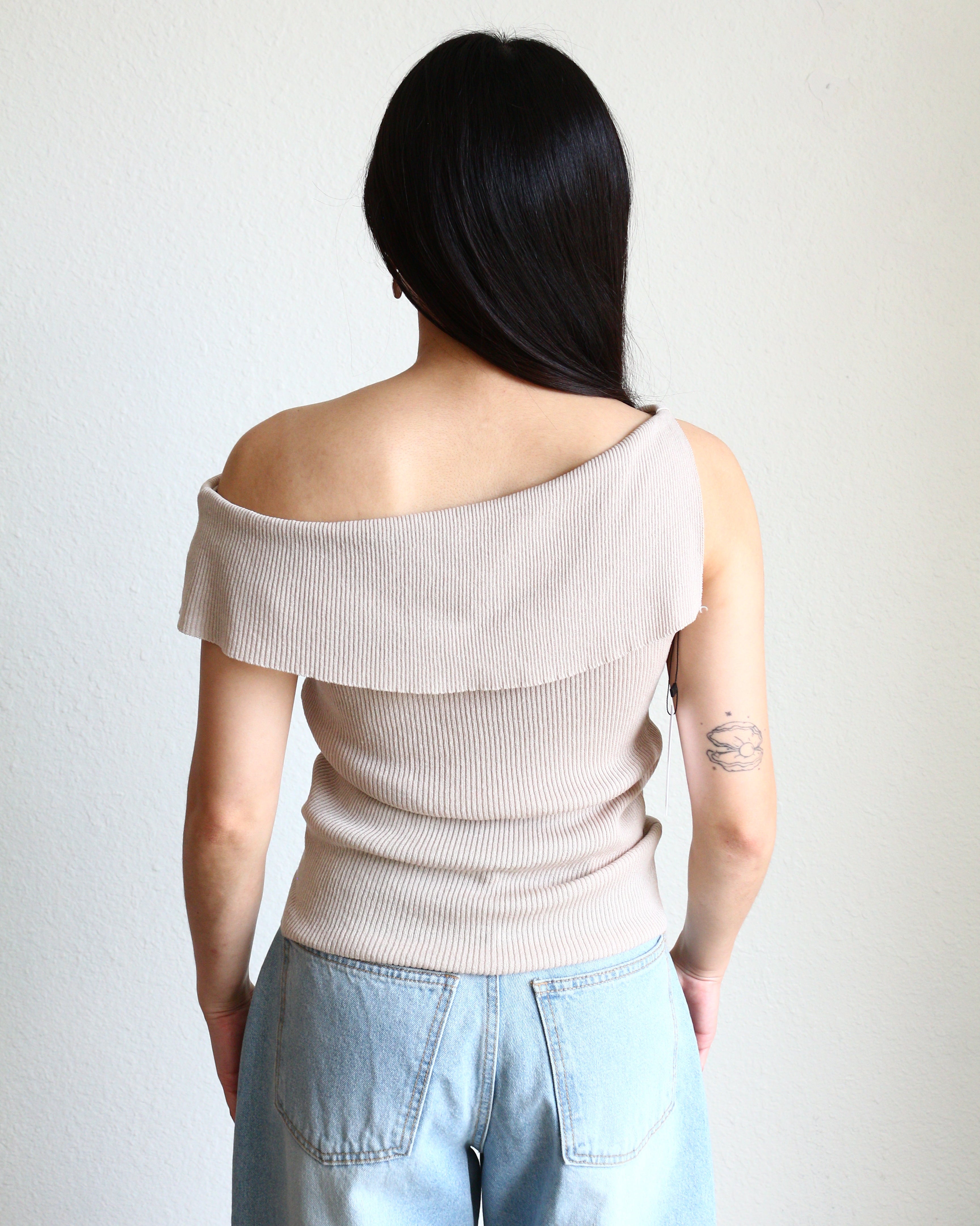 Woman wearing a beige Ribbed Off Shoulder Sleeveless Top and light blue jeans