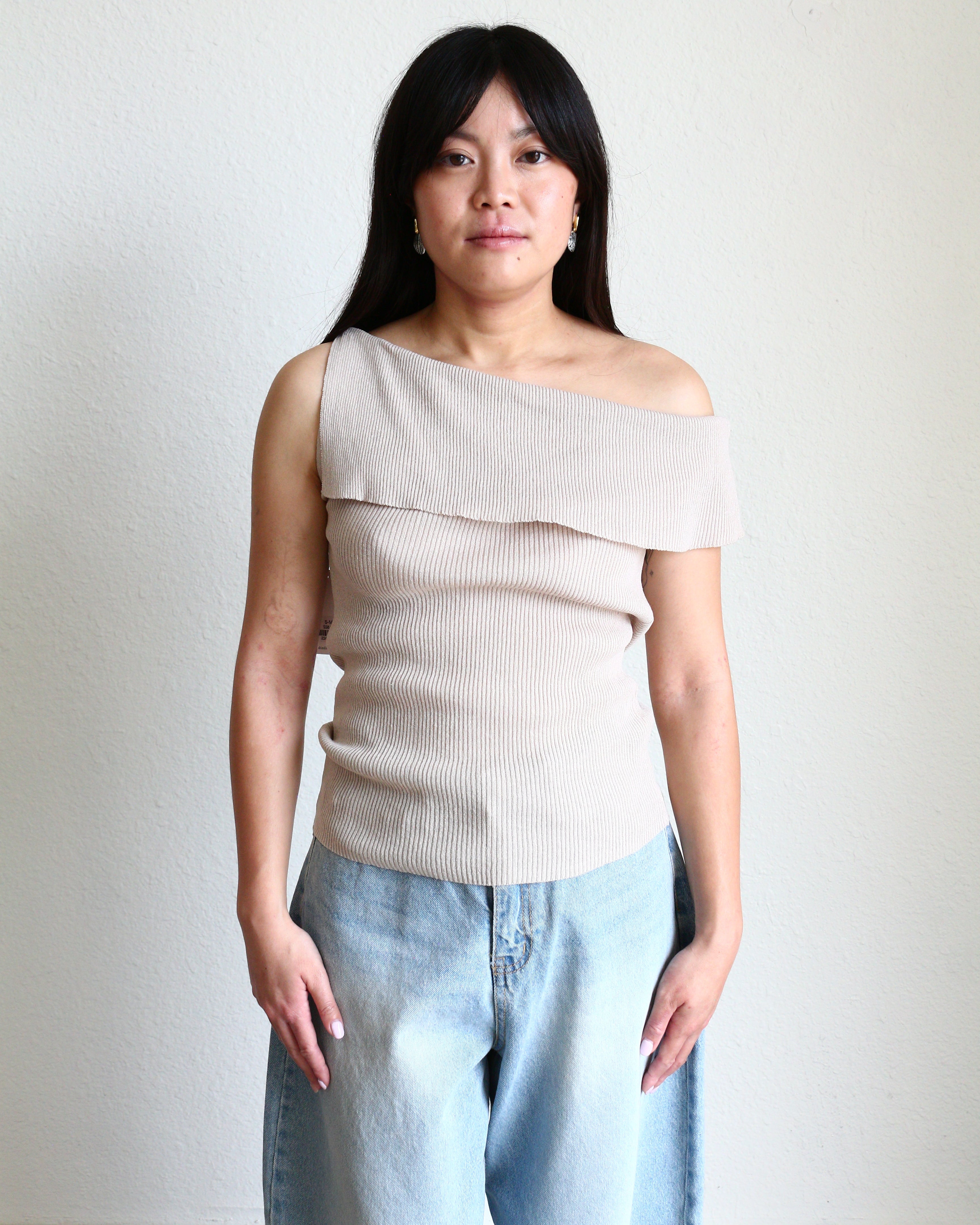 Woman wearing a beige Ribbed Off Shoulder Sleeveless Top and light blue jeans