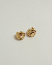 Pair of gold ridged earrings on a light gray background