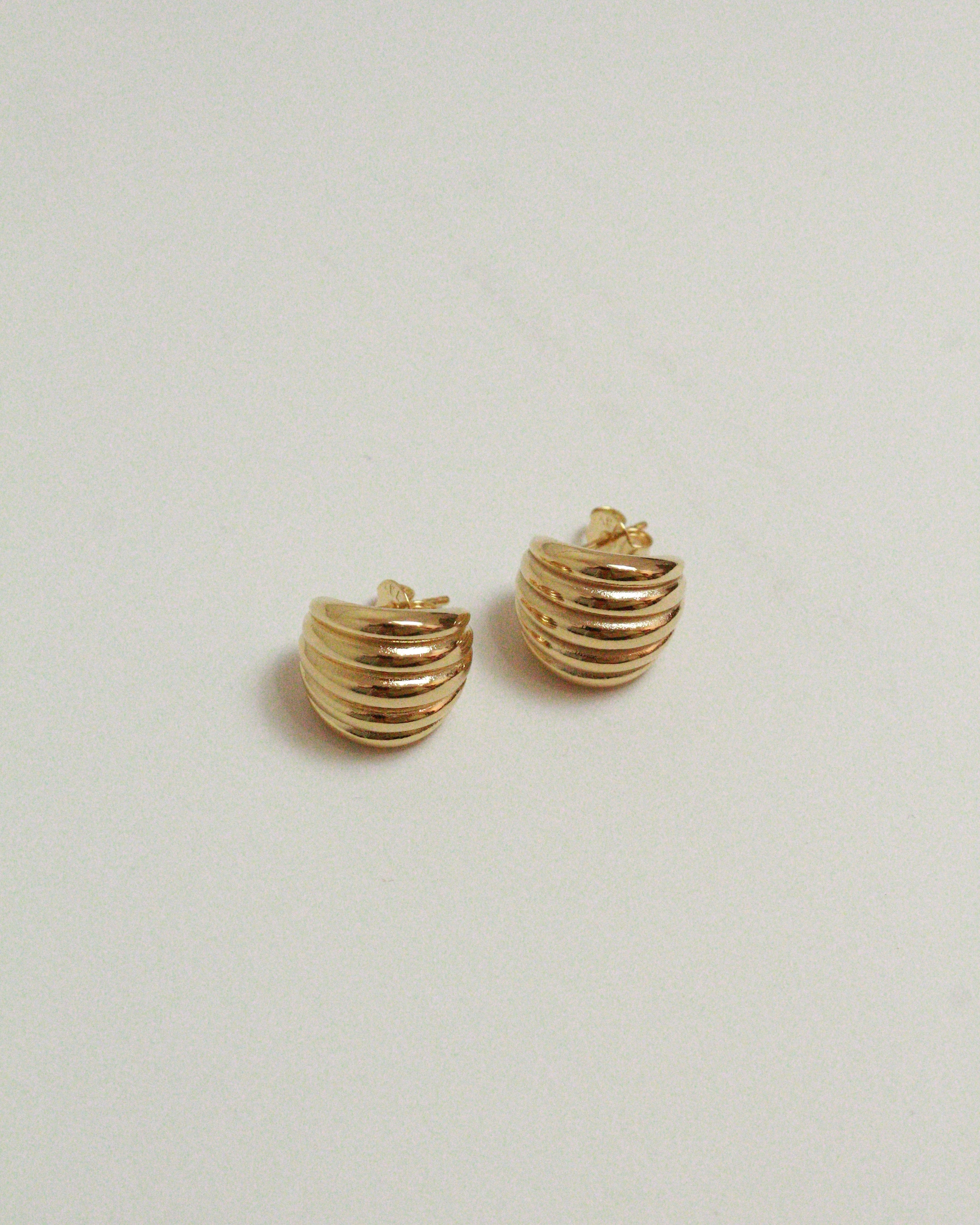 Pair of gold ridged earrings on a light gray background
