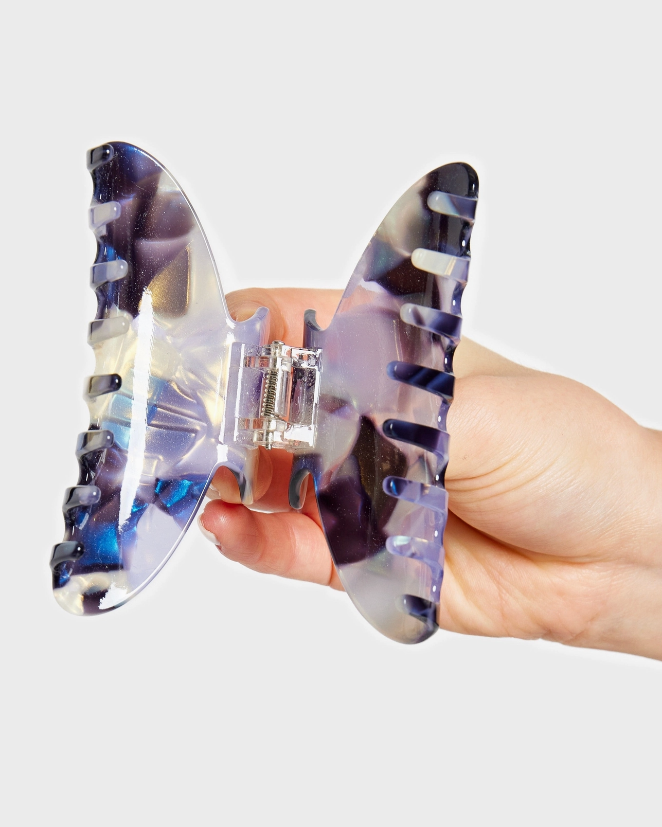 Clear plastic shark fin-shaped product held by a hand on a light gray background