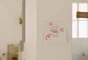 Children's drawing of a bear with a bow on a white wall.