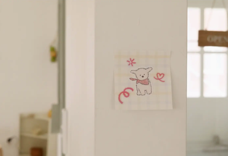 Children's drawing of a bear with a bow on a white wall.