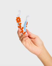 Hand holding a baby teether with floral design against a white background