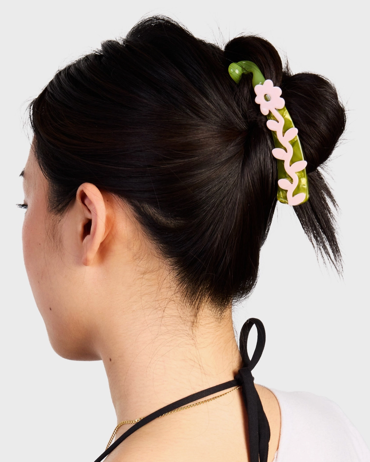 Woman with a floral hair clip in her bun against a white background
