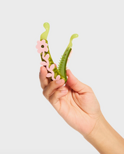 Hand holding a green and pink floral-shaped object against a white background