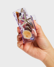 Hand holding a clear phone case with starfish and shells on a light gray background