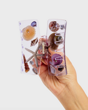 Phone case with seashell and starfish design held by a hand on a white background
