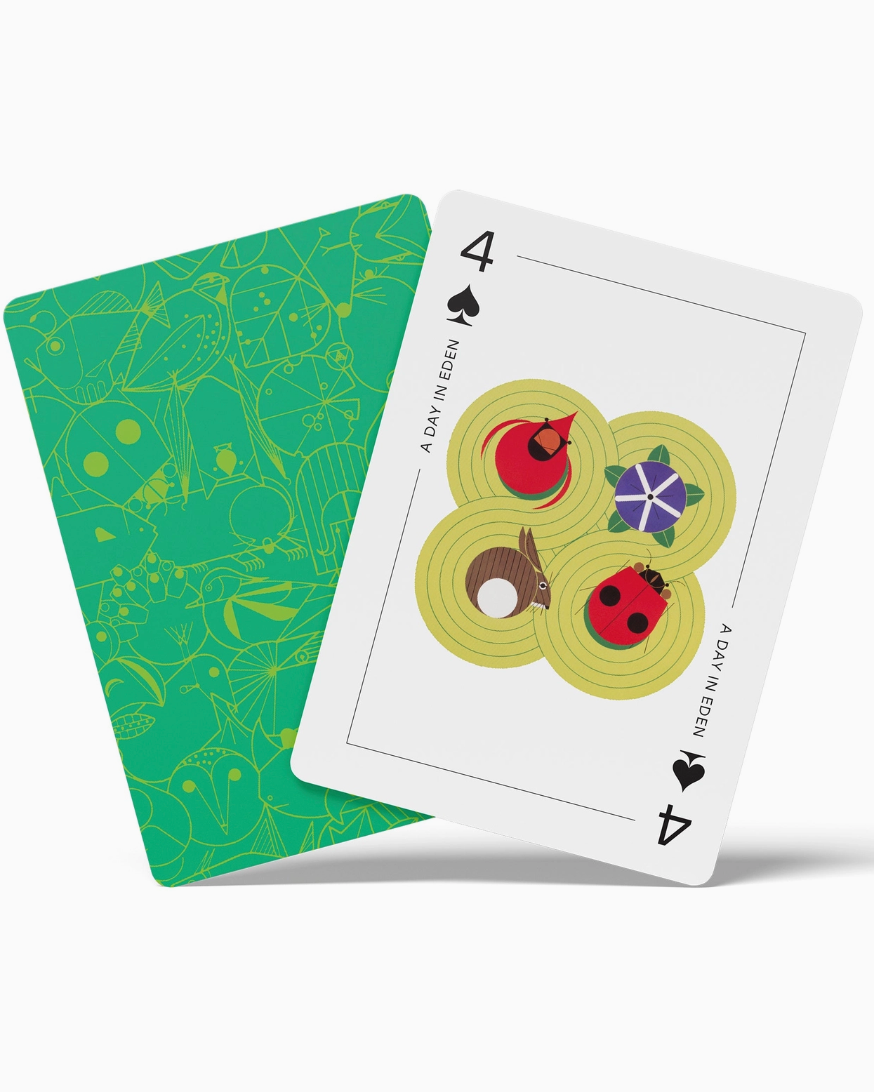 Two playing cards, one green with floral patterns and the other white with a design of four symbols, on a white background.