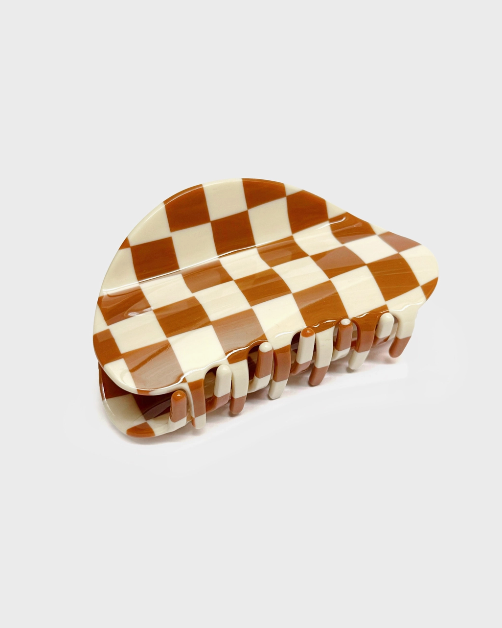 Checkered brown and white hair clip on a light gray background