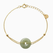 Gold bracelet with a green stone on a white background