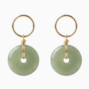 Pair of earrings with gold loops and green round stones on a white background