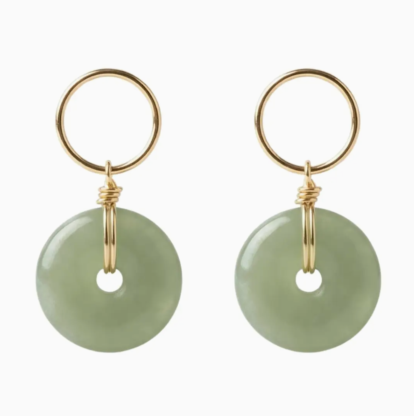 Pair of earrings with gold loops and green round stones on a white background