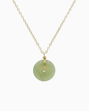 Gold necklace with a round diamond pendant on a white background