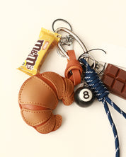 Keychain with brown leather glove, pool ball, candy bar, and lanyard on a white background