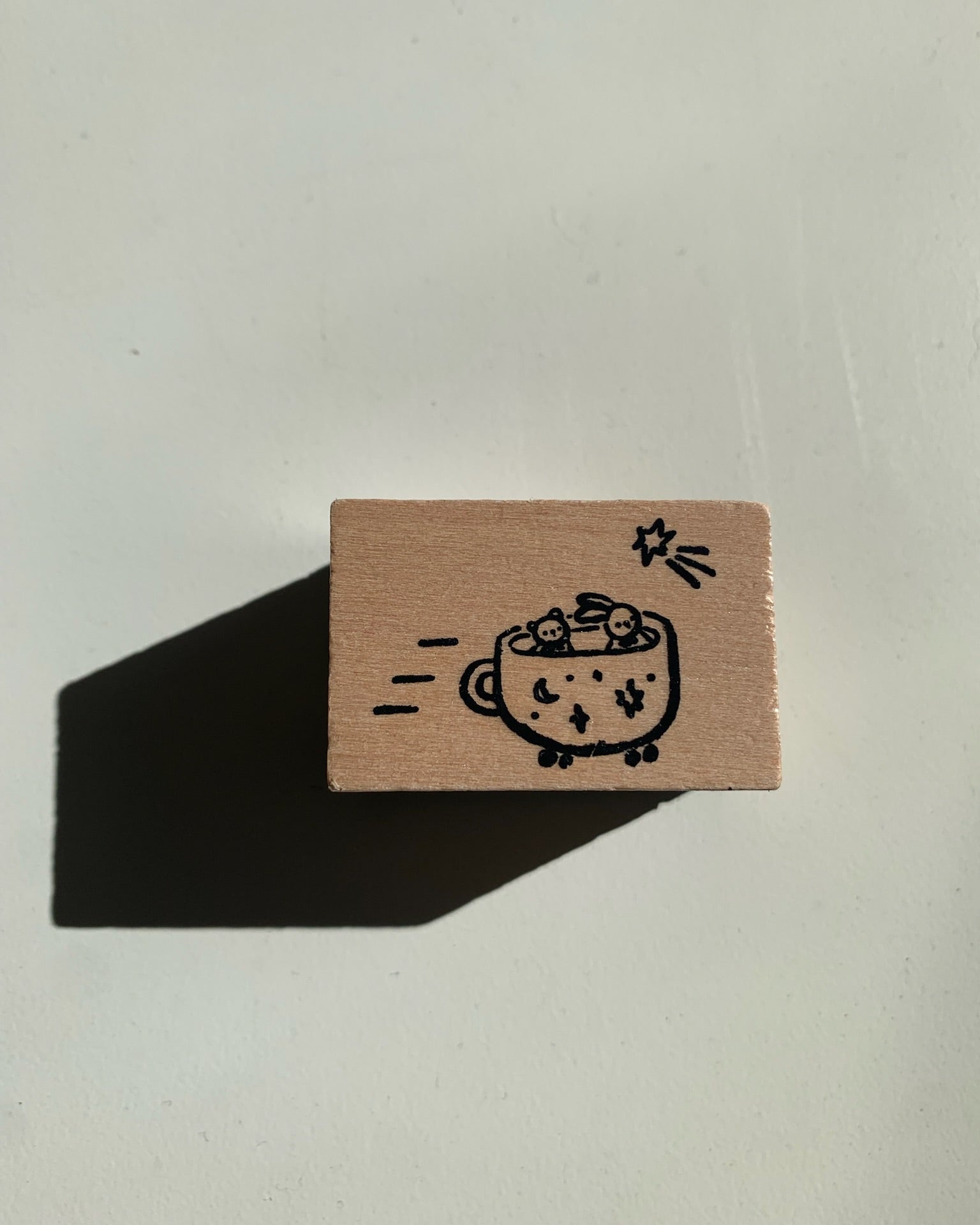 Small brown rubber stamp with a coffee cup design on a light gray background