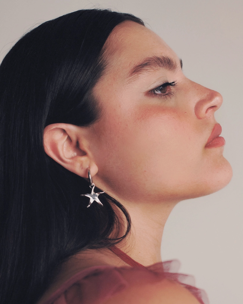 Woman wearing a star-shaped earring against a neutral background