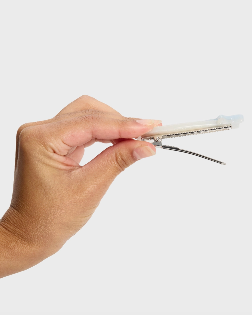 Hand holding a small metallic tool against a white background
