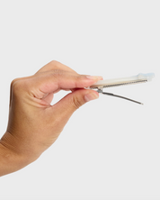 Hand holding a small metallic tool against a white background
