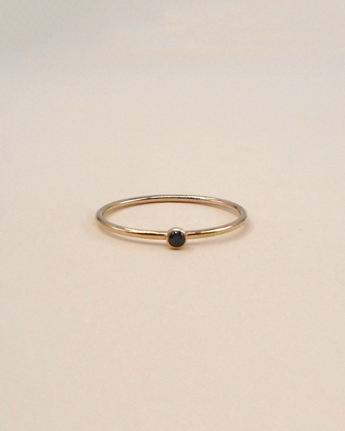 Gold ring with a black gemstone on a beige background