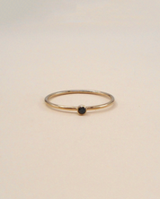 Gold ring with a black gemstone on a beige background