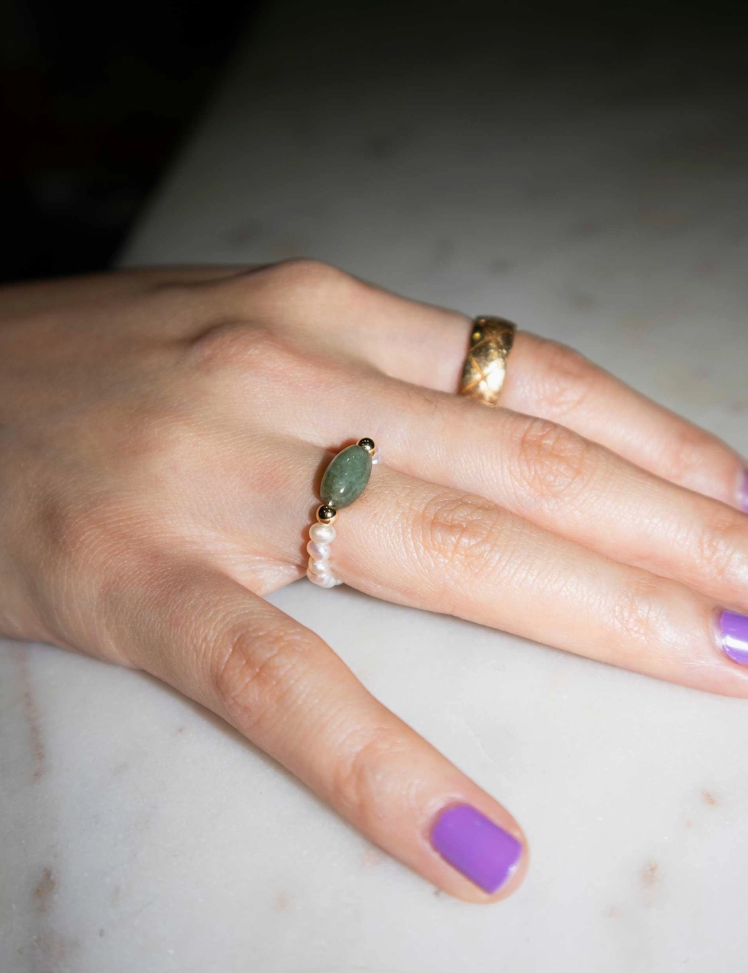 Hand with multiple rings on a marble surface