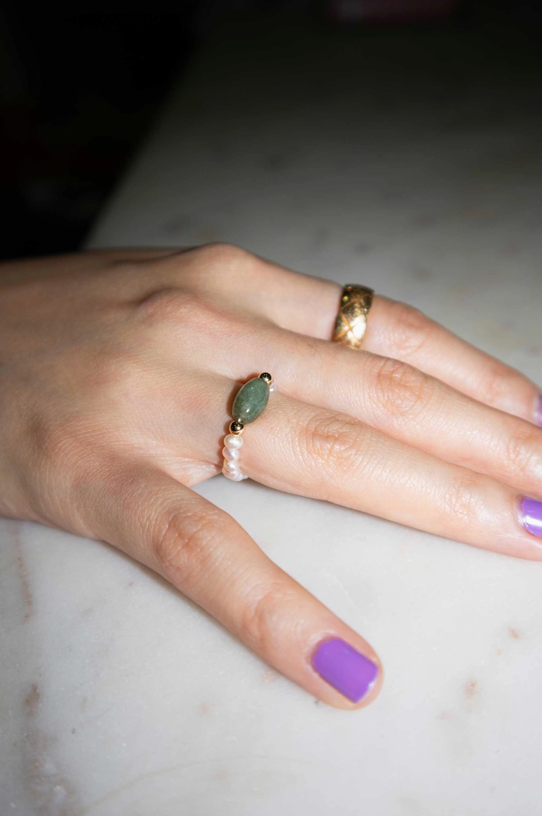 Hand with multiple rings on a marble surface