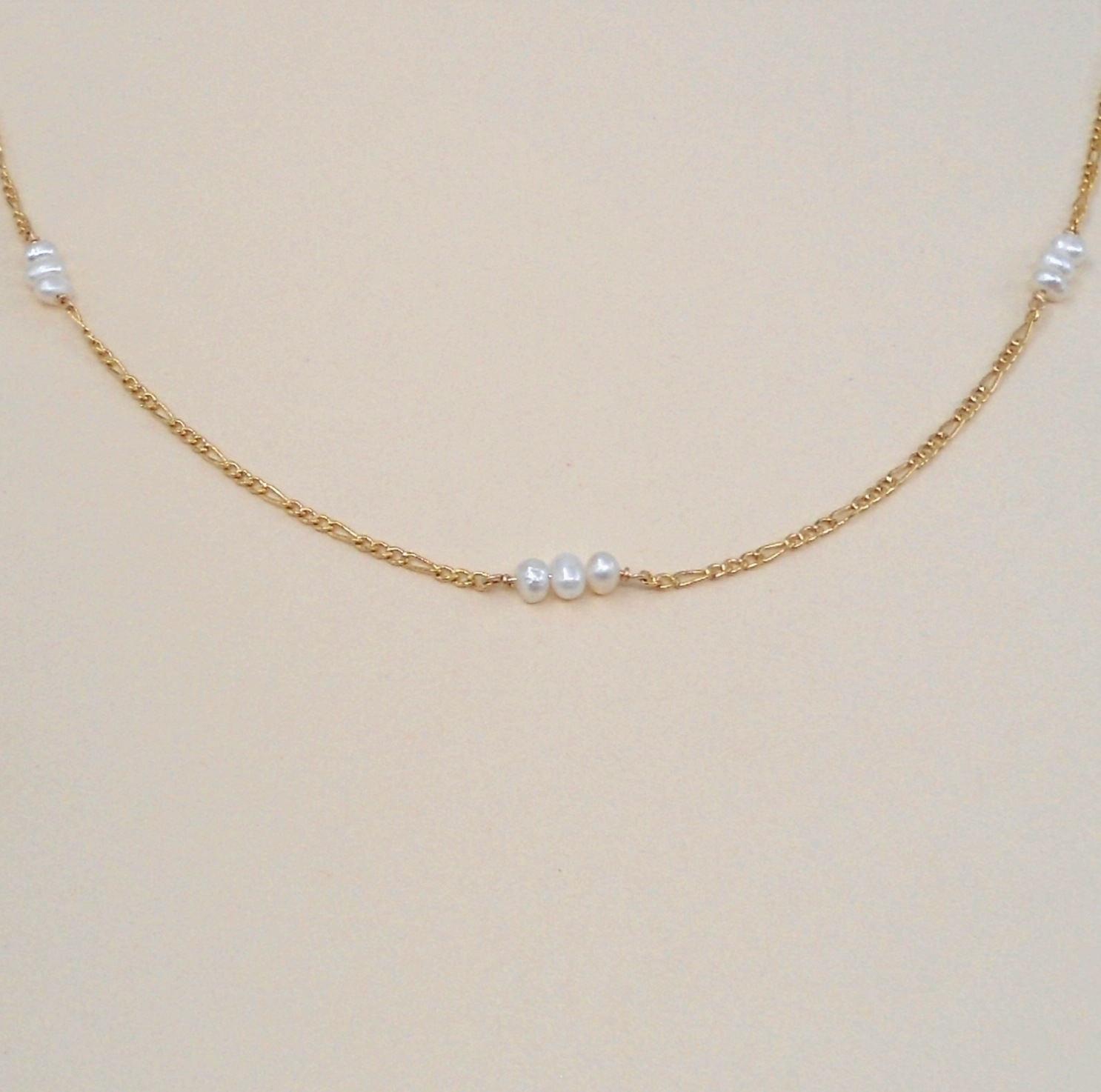 Gold chain necklace with pearls on a beige background